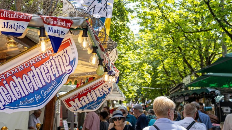 Menschen schlendern &uuml;ber den Hamburger Fischmarkt auf dem Karlsplatz, umgeben von St&auml;nden mit Matjes und Fischspezialit&auml;ten unter gr&uuml;nen B&auml;umen., &copy; Stuttgart-Marketing GmbH, Sarah Schmid