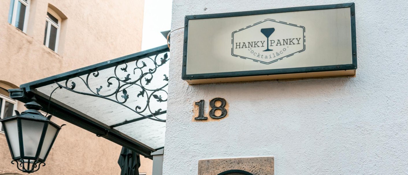 Ein Schild mit der Aufschrift 'Hanky Panky Cocktail & co' h&auml;ngt an einer Hauswand mit der Nummer 18. Eine Laterne und ein dekoratives Vordach sind sichtbar., &copy; Stuttgart-Marketing GmbH, Sarah Schmid