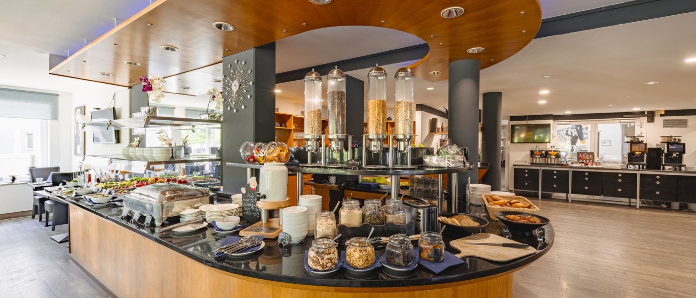 A rich breakfast buffet with muesli, pastries and fresh ingredients in a modern restaurant., © Plaza INN Stuttgart-Filderstadt A rich breakfast buffet with muesli, pastries and fresh ingredients in a modern restaurant., © Plaza INN Stuttgart-Filderstadt