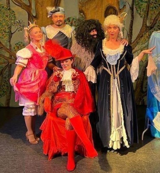 Actors in colorful costumes pose on a stage. They portray fairytale characters, including a person in red boots and a man with a long beard., &copy; Theater Atelier