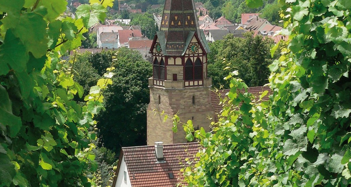 Die Pfarrkirche St. Andreas in Uhlbach ragt zwischen grünen Weinreben hervor, mit Hügeln und Häusern im Hintergrund., © Stuttgart-Marketing GmbH Die Pfarrkirche St. Andreas in Uhlbach ragt zwischen grünen Weinreben hervor, mit Hügeln und Häusern im Hintergrund., © Stuttgart-Marketing GmbH