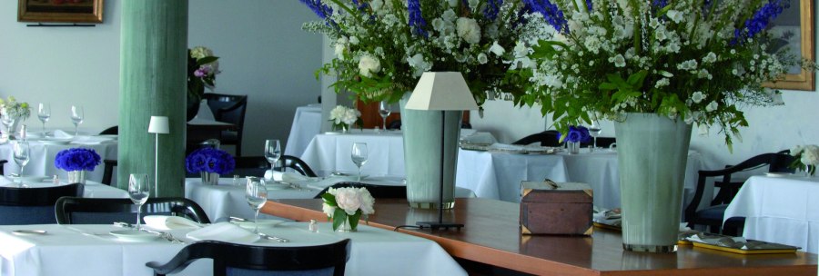Elegant restaurant with white tablecloths, large flower arrangements and stylish decoration. The atmosphere is sophisticated and inviting., &copy; Vincent Klinik