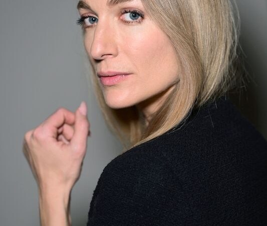 Frau mit blonden Haaren und schwarzem Oberteil blickt über die Schulter. Sie trägt ein Armband und hat einen ernsten Gesichtsausdruck., © Börsenverein des Deutschen Buchhandels, Landesverband Baden-Württemberg e.V.