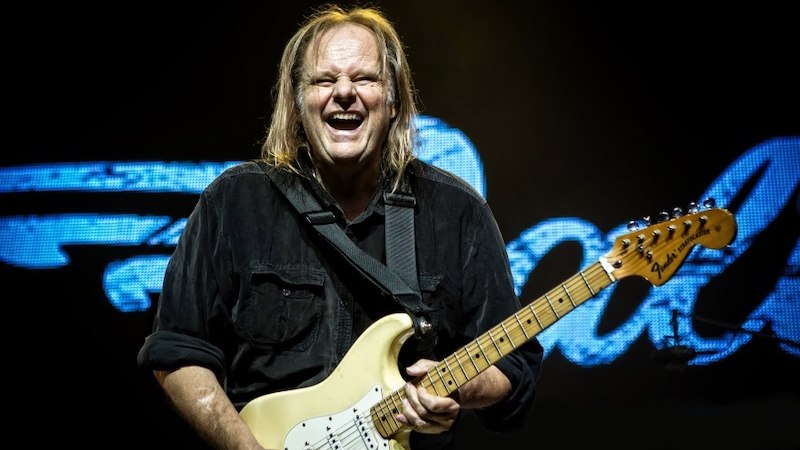 Ein Musiker mit langer Haaren spielt leidenschaftlich E-Gitarre auf der Bühne, im Hintergrund leuchtet ein Schriftzug., © Südwestdeutsche Konzertdirektion Michael Russ GmbH Ein Musiker mit langer Haaren spielt leidenschaftlich E-Gitarre auf der Bühne, im Hintergrund leuchtet ein Schriftzug., © Südwestdeutsche Konzertdirektion Michael Russ GmbH