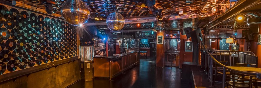 Club with vinyl records on the walls and ceiling, disco balls and bar. Atmospheric lighting and empty dance floor., © Goldmarks, Stuttgart Club with vinyl records on the walls and ceiling, disco balls and bar. Atmospheric lighting and empty dance floor., © Goldmarks, Stuttgart