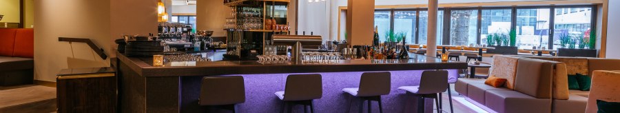 Modern bar with stylish lighting, high stools and cozy seating areas. The atmosphere is inviting and elegant., © Breuninger