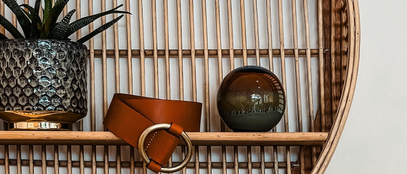 A shelf with a plant in a textured pot, a brown belt with a golden buckle and a round ceramic vase., © MAGASIN Geißstrasse 15, Stuttgart