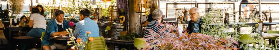 A lively outdoor café with people sitting at tables under parasols. Plants and decorations create a cozy atmosphere., © SMG Stuttgart Marketing GmbH - Sarah Schmid