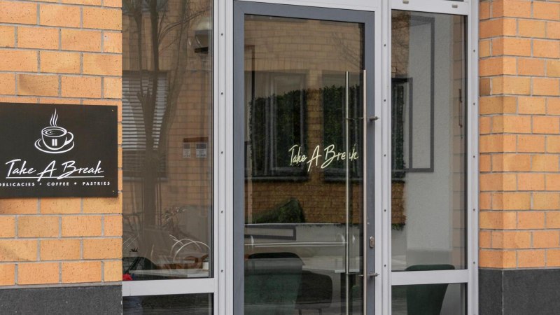 Eingang des Caf&eacute;s mit dem Namen 'Take A Break'. Ein Schild zeigt eine Tasse Kaffee und die Aufschrift 'Delicacies, Coffee, Pastries'., &copy; Stuttgart-Marketing GmbH, Sarah Schmid