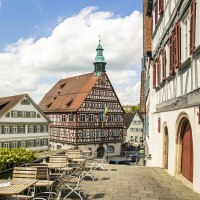 A view of historic half-timbered houses in Backnang. In the foreground are empty seats; in the background is a blue sky with clouds., &copy; SMG Stuttgart Marketing GmbH - Sarah Schmid