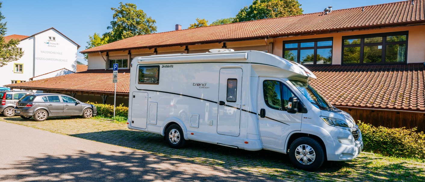Ein Wohnmobil steht auf einem Parkplatz vor einem Geb&auml;ude mit rotem Ziegeldach und blauen Himmel im Hintergrund., &copy; Stuttgart-Marketing GmbH, Thomas Niederm&uuml;ller