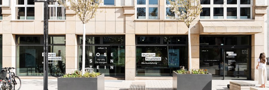 Eingang zur Ausstellung Stuttgart Rosenstein mit Glasfront, Schriftzug und Bäumen. Eine Person steht rechts, Fahrräder links., © Stadt Stuttgart / Dominique Brewing