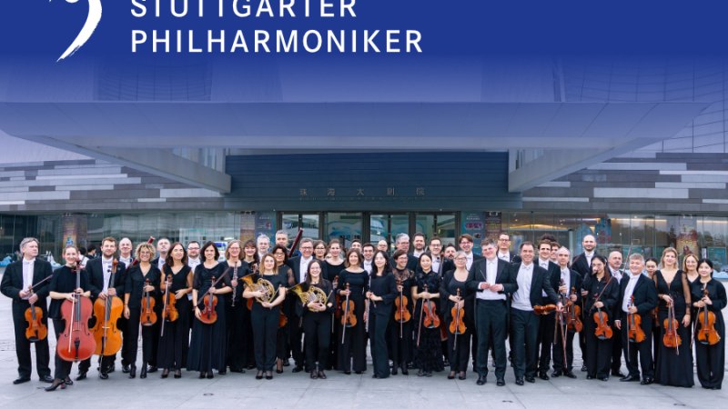 Die Stuttgarter Philharmoniker posieren mit ihren Instrumenten vor einem modernen Gebäude. Oben ist ihr Logo und Name zu sehen., © Juan Carlos Rivas Perretta, Stuttgarter Philharmoniker Die Stuttgarter Philharmoniker posieren mit ihren Instrumenten vor einem modernen Gebäude. Oben ist ihr Logo und Name zu sehen., © Juan Carlos Rivas Perretta, Stuttgarter Philharmoniker