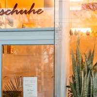 Entrance of a store with the lettering 'Tanzschuhe' above the door. Plants and warm lighting can be seen inside., © SMG, Sarah Schmid Entrance of a store with the lettering 'Tanzschuhe' above the door. Plants and warm lighting can be seen inside., © SMG, Sarah Schmid