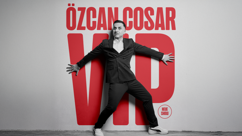 Ein Mann in einem Anzug posiert dramatisch vor einem gro&szlig;en roten Schriftzug '&Ouml;zcan Cosar VIP'., &copy; links im Bild