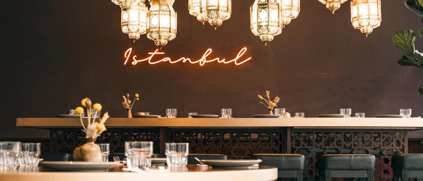 A stylishly furnished restaurant with oriental lamps and glowing "Istanbul" neon lettering on the wall., © Noa, Stuttgart