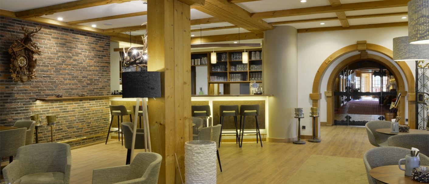 Cozy hotel bar with wooden beams, brick wall, modern furniture and a large archway in the background., © TOMAS