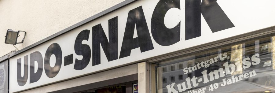 Schild mit der Aufschrift 'UDO-SNACK', darunter 'Stuttgarts Kult-Imbiss seit über 40 Jahren'. Außenansicht eines Imbissladens., © SMG, Sarah Schmid
