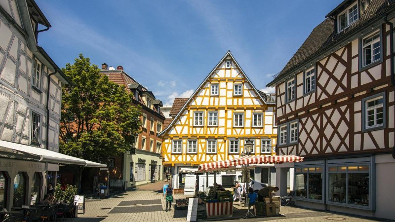 Half-timbered houses in the old town of Backnang, surrounded by market stalls and passers-by in sunny weather., &copy; Stuttgart-Marketing GmbH, Sarah Schmid