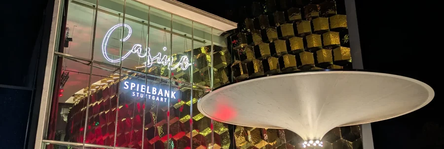 Die Spielbank Stuttgart bei Nacht: beleuchtete Glasfassade, goldene Kubusstruktur und markantes weißes Schirmdach., © SMG Die Spielbank Stuttgart bei Nacht: beleuchtete Glasfassade, goldene Kubusstruktur und markantes weißes Schirmdach., © SMG