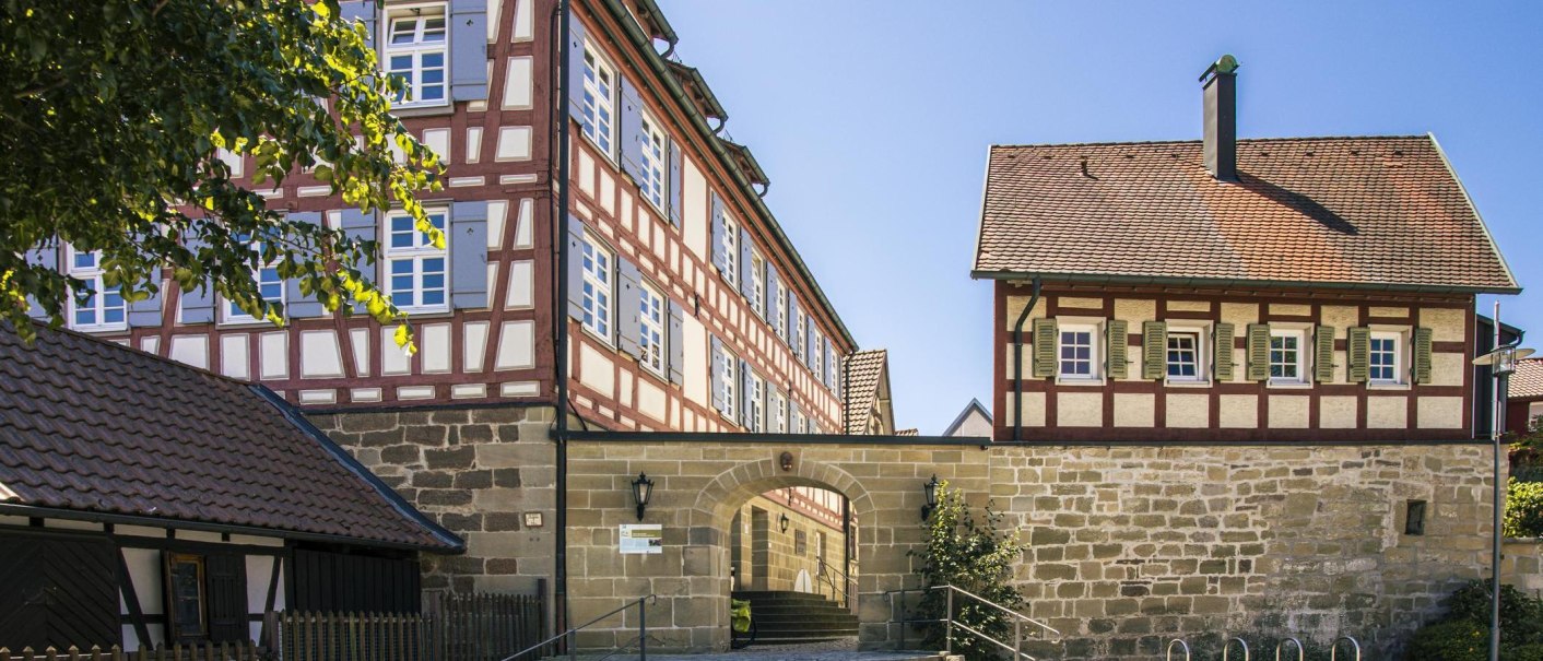 Half-timbered houses in the old town of Murrhardt, Germany. The buildings have red and white facades with blue shutters against a clear sky., © SMG Stuttgart Marketing GmbH - Sarah Schmid Half-timbered houses in the old town of Murrhardt, Germany. The buildings have red and white facades with blue shutters against a clear sky., © SMG Stuttgart Marketing GmbH - Sarah Schmid