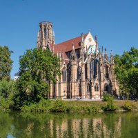 Die Johanneskirche am Feuersee in Stuttgart, umgeben von B&auml;umen und reflektiert im Wasser, bei klarem, sonnigem Wetter., &copy; SMG Achim Mende