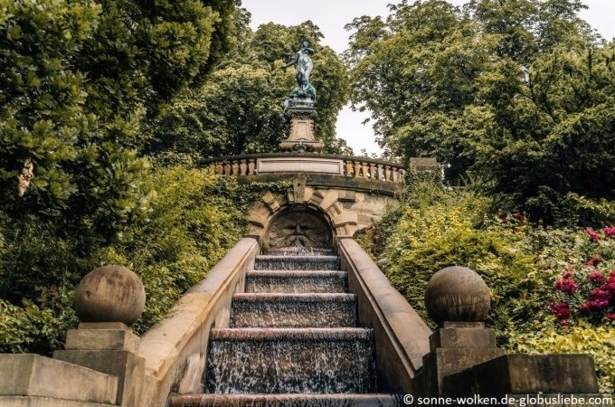 Steintreppe mit Wasserfall, flankiert von B&auml;umen und Str&auml;uchern, f&uuml;hrt zu einer Statue auf einer Balustrade., &copy; Stuttgart Marketing GmbH