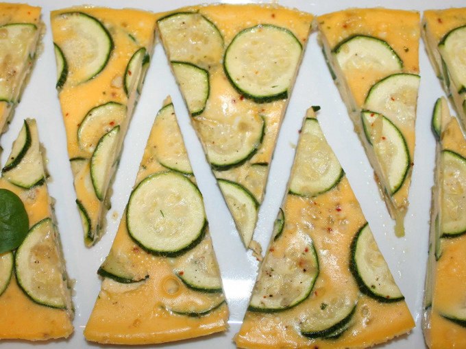 Triangular pieces of zucchini frittata on a white plate, decoratively arranged., &copy; Kultweine-Kochwelten-Kunst&uuml;cke - Kochschule Sonja Lenz