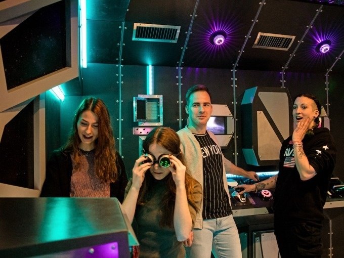 Four people in a futuristic room with lights and consoles. One person is wearing glasses, the others are looking around with interest., © ExitGames Stuttgart Four people in a futuristic room with lights and consoles. One person is wearing glasses, the others are looking around with interest., © ExitGames Stuttgart