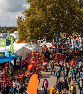 Eine belebte Messe mit zahlreichen Besuchern, Ständen und landwirtschaftlichen Maschinen. Bunte Fahnen und Zelte prägen das Bild., © Daniel Schneider, 2022 Eine belebte Messe mit zahlreichen Besuchern, Ständen und landwirtschaftlichen Maschinen. Bunte Fahnen und Zelte prägen das Bild., © Daniel Schneider, 2022