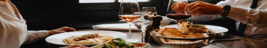 Zwei Personen genießen ein Essen in einem Restaurant. Auf dem Tisch stehen Wein, Brot und Salat. Die Atmosphäre wirkt gemütlich und elegant., © Stuttgart-Marketing GmbH, Alwin Maigler