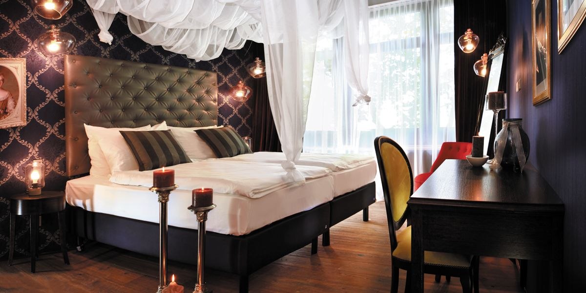 Elegant bedroom with four-poster bed, dark furniture, candles and stylish decoration. Large windows let in plenty of light., &copy; TOMAS