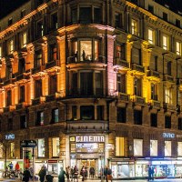 A large, illuminated building at night with stores on the first floor and people on the street., &copy; Schauspielb&uuml;hnen in Stuttgart