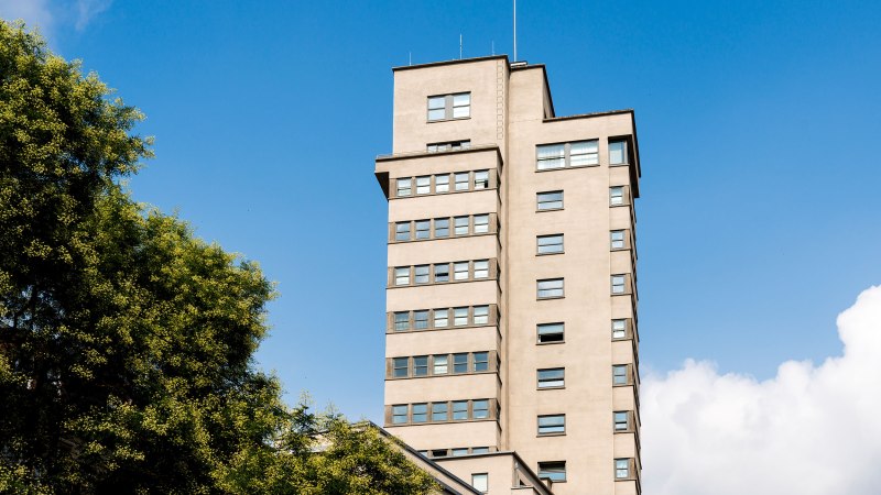 Der Tagblatt-Turm in Stuttgart erhebt sich vor einem klaren blauen Himmel, umgeben von grünen Bäumen., © TMBW, Gregor Lengler Der Tagblatt-Turm in Stuttgart erhebt sich vor einem klaren blauen Himmel, umgeben von grünen Bäumen., © TMBW, Gregor Lengler