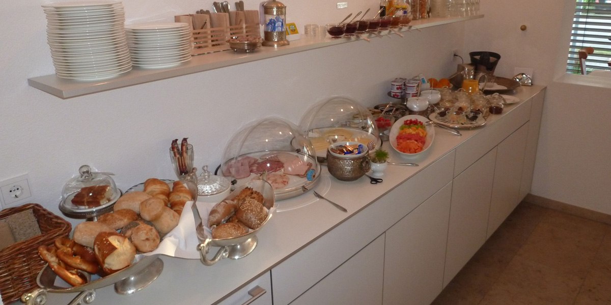 Ein reichhaltiges Frühstücksbüffet mit Brötchen, Aufschnitt, Obst und Joghurt auf einer weißen Theke., © Hotelmärchen Ein reichhaltiges Frühstücksbüffet mit Brötchen, Aufschnitt, Obst und Joghurt auf einer weißen Theke., © Hotelmärchen