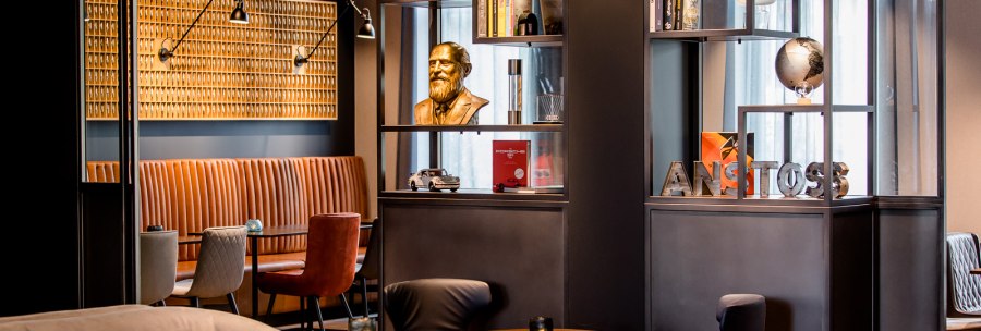 Moderne Lounge mit gemütlichen Sitzgelegenheiten, Bücherregalen und Dekorationen wie einer Büste und einem Globus. Elegantes, stilvolles Ambiente., © TOMAS Moderne Lounge mit gemütlichen Sitzgelegenheiten, Bücherregalen und Dekorationen wie einer Büste und einem Globus. Elegantes, stilvolles Ambiente., © TOMAS