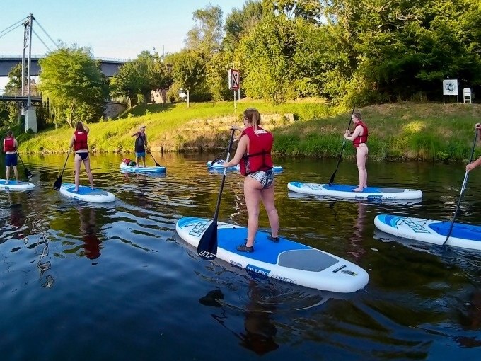 Eine Gruppe von Menschen in roten Schwimmwesten macht einen SUP-Anf&auml;ngerkurs auf einem ruhigen Fluss, umgeben von gr&uuml;ner Natur., &copy; Cool-Tours StattReisen