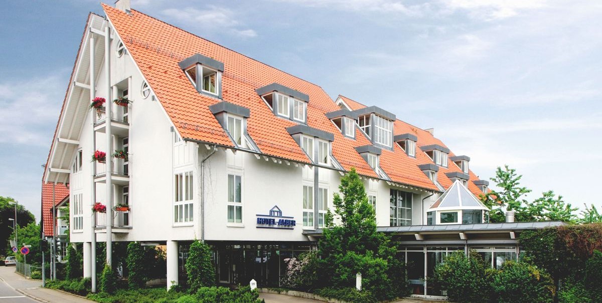 Modernes Hotel mit roten Ziegeld&auml;chern und wei&szlig;en W&auml;nden, umgeben von B&auml;umen und Pflanzen, an einer Stra&szlig;e gelegen., &copy; Hotel Alber KG