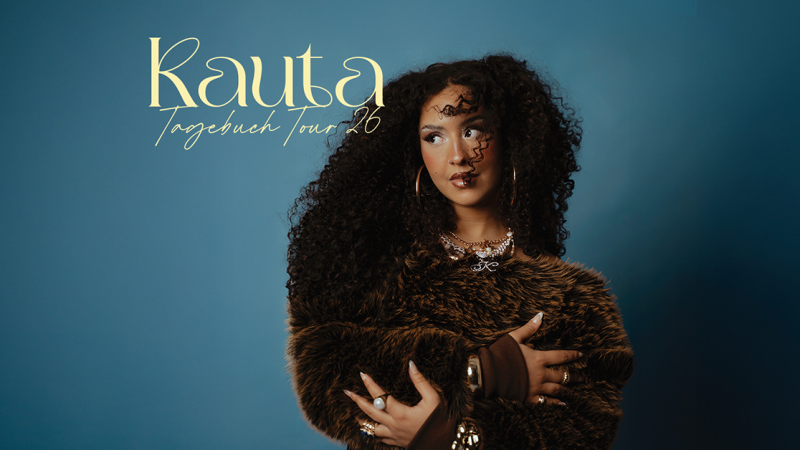 Eine Frau mit lockigem Haar und einem Pelzmantel posiert vor einem blauen Hintergrund. Der Text 'Kauta Tagebuch Tour 2026' ist eingeblendet., © links im Bild Eine Frau mit lockigem Haar und einem Pelzmantel posiert vor einem blauen Hintergrund. Der Text 'Kauta Tagebuch Tour 2026' ist eingeblendet., © links im Bild