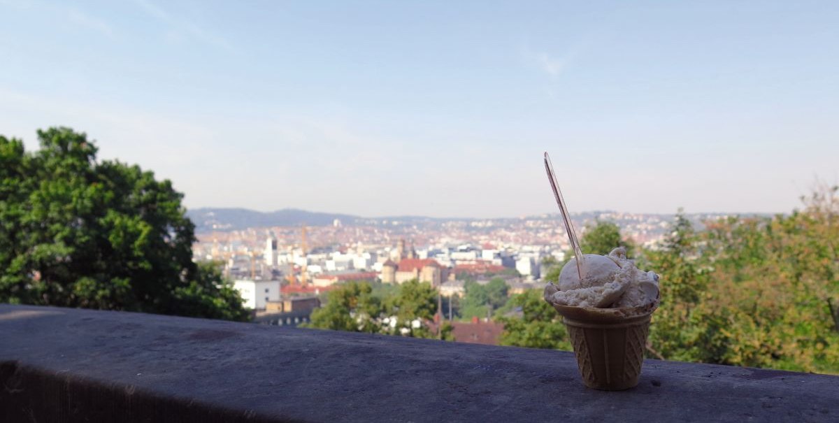 Ein Eisbecher steht auf einer Mauer mit Blick auf die Stadt Stuttgart vom Eugensplatz aus. Im Hintergrund sind Bäume und Gebäude zu sehen., © Stuttgart-Marketing GmbH Ein Eisbecher steht auf einer Mauer mit Blick auf die Stadt Stuttgart vom Eugensplatz aus. Im Hintergrund sind Bäume und Gebäude zu sehen., © Stuttgart-Marketing GmbH