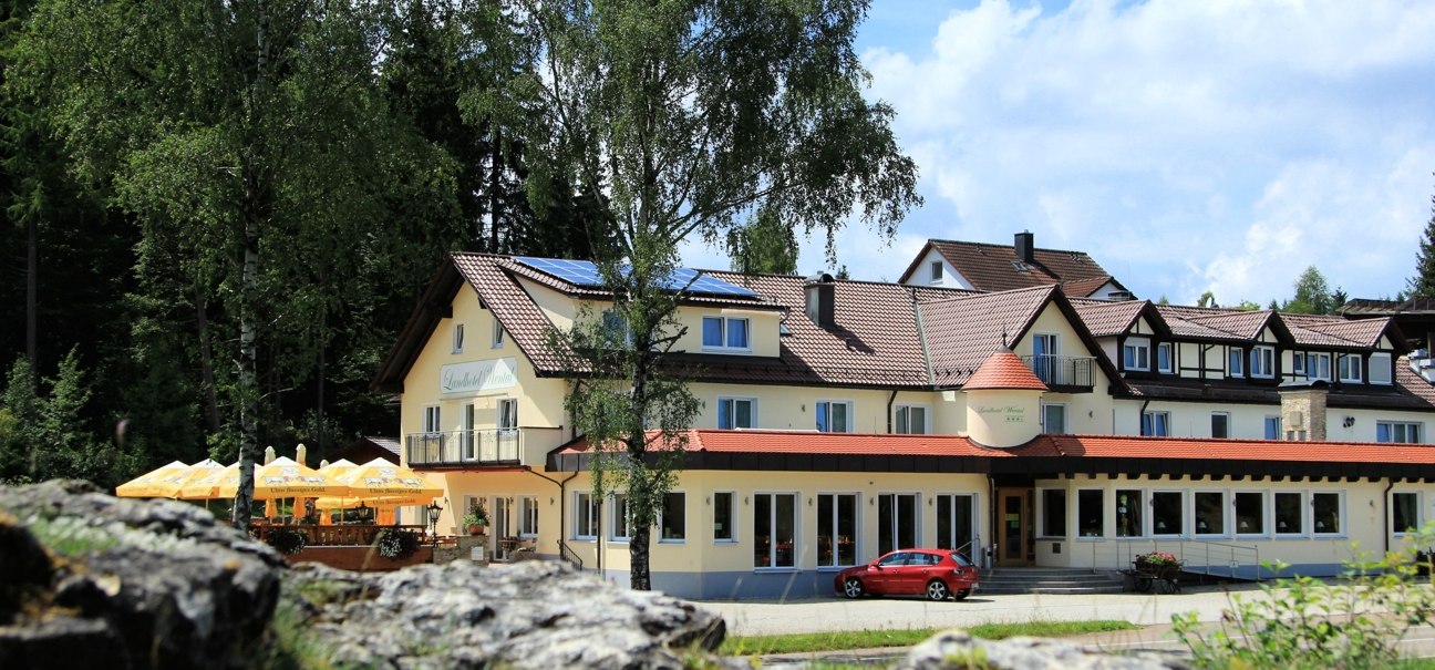 The Landhotel Wental in Bartholomä, surrounded by trees. A red car is parked in front of it, parasols are set up. The sky is blue with a few clouds., © Landhotel Wental The Landhotel Wental in Bartholomä, surrounded by trees. A red car is parked in front of it, parasols are set up. The sky is blue with a few clouds., © Landhotel Wental
