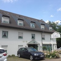 Das Aparthotel Wangener Landhaus mit grauem Dach und weißen Wänden. Vor dem Gebäude sind Autos geparkt. Ein Schild zeigt den Hotelnamen., © Aparthotel Wangener Landhaus Das Aparthotel Wangener Landhaus mit grauem Dach und weißen Wänden. Vor dem Gebäude sind Autos geparkt. Ein Schild zeigt den Hotelnamen., © Aparthotel Wangener Landhaus
