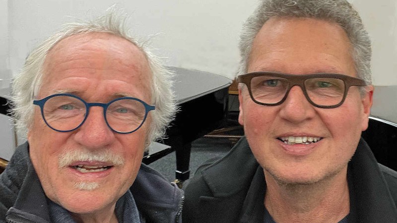 Zwei M&auml;nner mit Brillen l&auml;cheln in die Kamera, im Hintergrund ist ein Fl&uuml;gel zu sehen., &copy; sDELTA