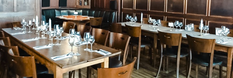 Elegantes Restaurant mit Holzwänden, gedeckten Tischen und Kerzenlicht. Dunkle Holzmöbel und eine gemütliche Atmosphäre dominieren den Raum., © Weinstube Fröhlich Verwaltungs GmbH