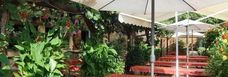 Cozy outdoor area with tables, benches, parasols and lush plants in a broom restaurant., &copy; Simone Mack