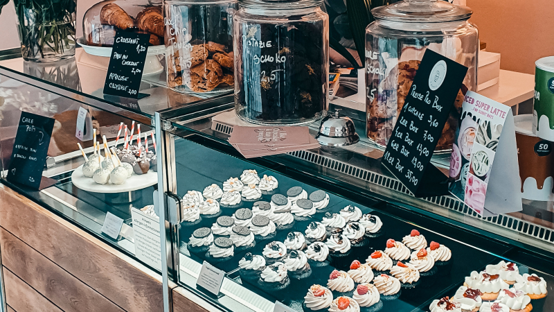 Eine Vitrine in einem Café zeigt eine Auswahl an Cupcakes, Cake Pops und Gebäck. Daneben stehen Gläser mit Keksen und Preisschilder., © Cupcakes & Bagels, Stuttgart Eine Vitrine in einem Café zeigt eine Auswahl an Cupcakes, Cake Pops und Gebäck. Daneben stehen Gläser mit Keksen und Preisschilder., © Cupcakes & Bagels, Stuttgart