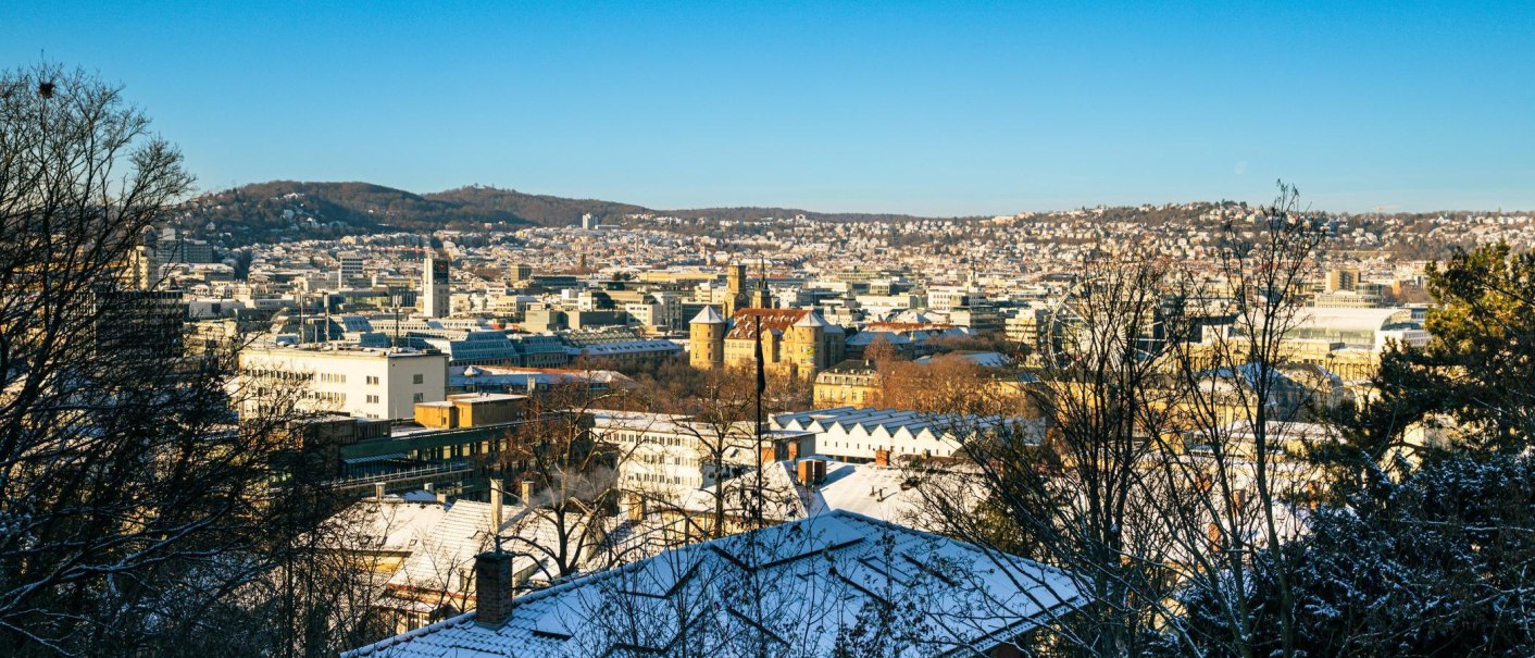 Winter panoramic view of Stuttgart with snow-covered roofs and a clear sky. The city extends to the wooded hills in the background., &copy; Stuttgart-Marketing GmbH, Sarah Schmid