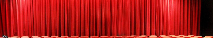 Empty theater hall with red chairs and closed red curtain, lighting and loudspeakers on the ceiling., © Sabine Haymann