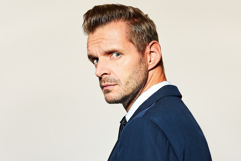 A man in a blue suit looks seriously to the side. The background is kept neutral, which draws the focus to his face., &copy; Theaterhaus Stuttgart e.V.