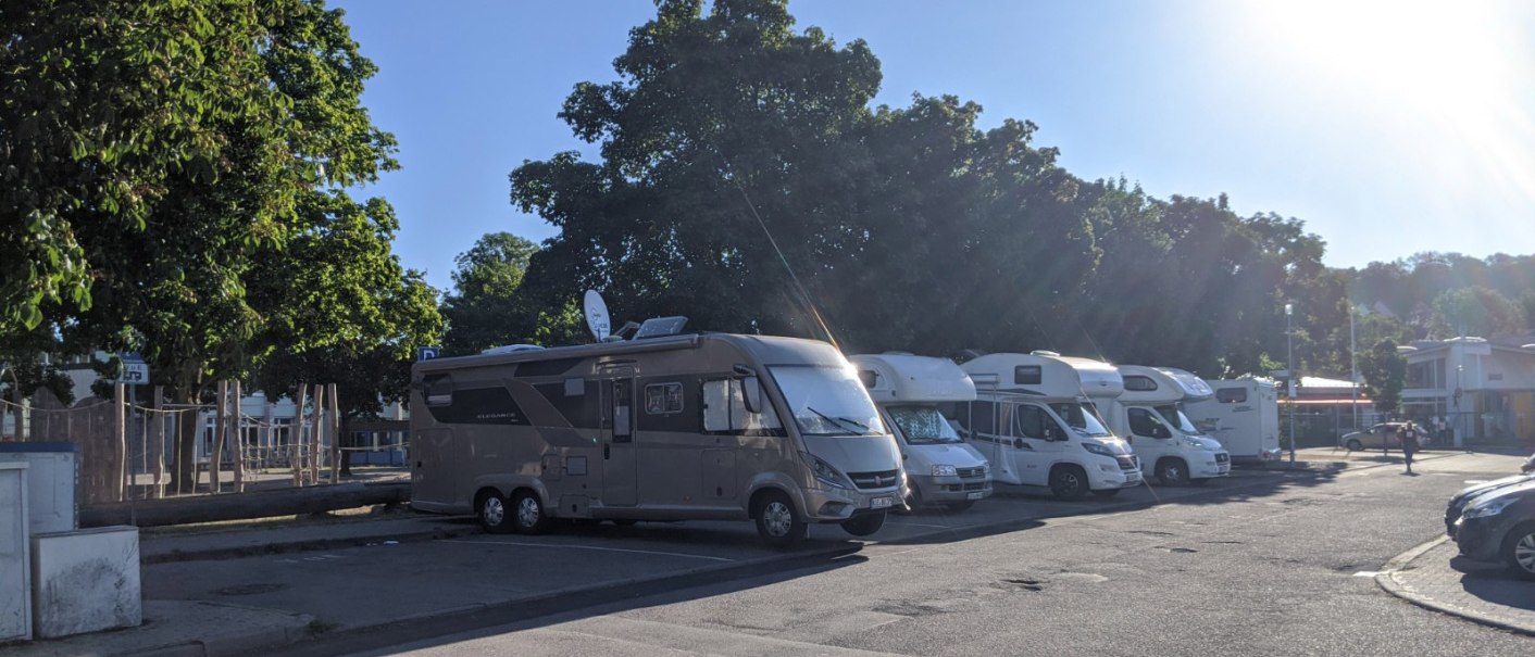 Wohnmobilstellplatz mit mehreren geparkten Wohnmobilen unter B&auml;umen bei Sonnenschein., &copy; Stadtverwaltung Weil der Stadt
